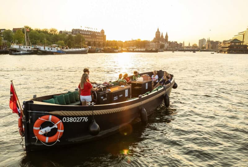 Open boat with skipper at sunset on the Amsterdam canals