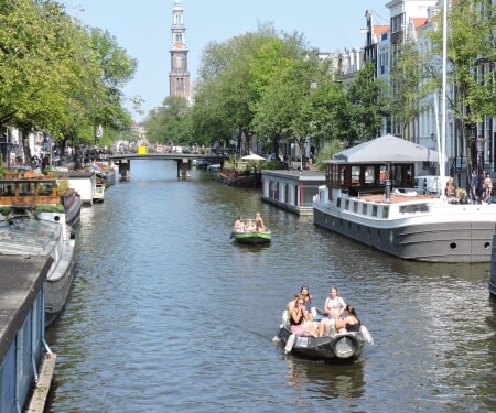 Two boats sailing along the Amsterdam canals.